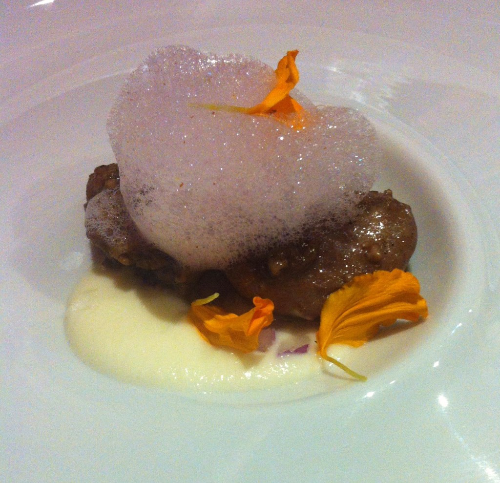 Castañetas de cerdo ibérico confitadas sobre crema de cebolleta fresca ligeramente ahumada. Membrillo y espuma de vino de la bota.